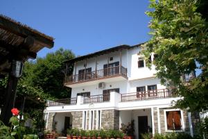 un gran edificio blanco con balcones y árboles en Hotel Vrionis en Agios Dimitrios