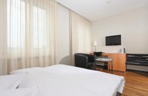 a hotel room with a bed and a desk and a television at Art Déco Hotel Elite in Biel
