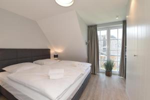 Cette chambre comprend un grand lit blanc et une fenêtre. dans l'établissement Gilde Hus, à Westerland