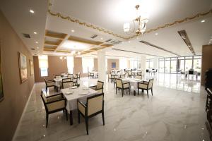 a dining room with white tables and chairs at Hotel Holiday in Koplik