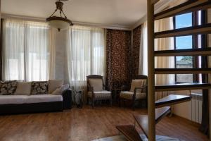 ein Wohnzimmer mit einem Sofa, Stühlen und Fenstern in der Unterkunft Guest House Yana in Batumi
