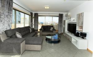 a living room with a couch and a tv at Exclusive Luxury Apartments in Oceano Atlantico Complex in Portimão