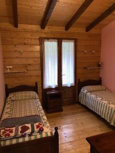 two beds in a room with wooden floors and windows at Ecoday camping in Fanano