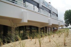 a building on the beach with tall grass at ACQUA Strande Yachthotel & Restaurant in Strande