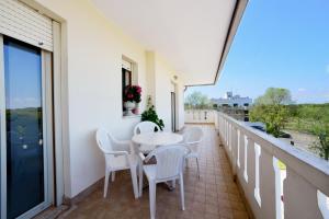 einen Balkon mit weißen Stühlen und einem Tisch auf dem Balkon in der Unterkunft Condominio Al Cigno in Lignano Sabbiadoro