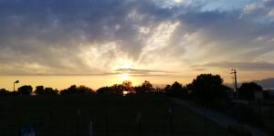 a sunset over a field with a fence and trees at La Maison du Port in Lazise