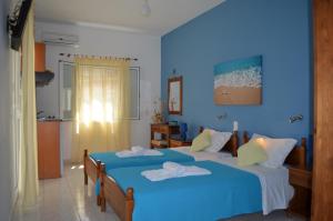 a blue bedroom with two beds with towels on them at Athena Kythera in Dhiakofti