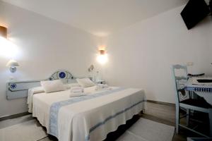 una camera da letto bianca con un letto e asciugamani di Villa Dessena Bed and Breakfast a Cala Liberotto