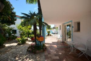 a patio with a palm tree and a table and chairs at Villa Dessena Guest House in Cala Liberotto