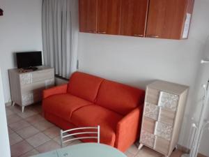 salon z czerwoną kanapą i telewizorem w obiekcie Villa Augusta w mieście Auronzo di Cadore