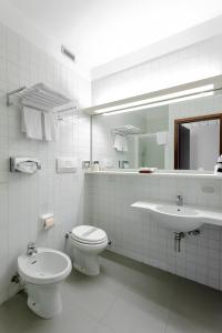 a white bathroom with a toilet and a sink at Grand Hotel President in Spilimbergo