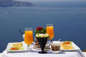 a table with two plates of food and two glasses of orange juice at Cori Rigas Suites in Fira