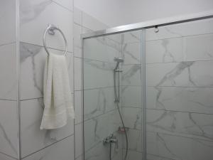 a shower with a glass door and a white towel at Oruci Apartments in Ksamil