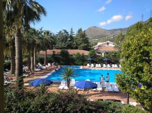 a pool with chairs and umbrellas and people standing around it at Villaggio Turistico La Mantinera - Residence in Praia a Mare