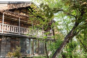 a wooden house with a balcony in the trees at Noka Minshuku Sanzen in Tokamachi