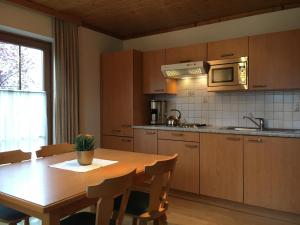a kitchen with a wooden table with chairs and a microwave at Ferienhaus Alpenland in Flachau