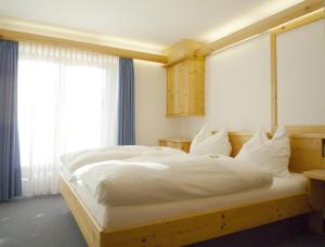 een slaapkamer met een groot bed met witte lakens bij Haus Sylvest in Oberstdorf