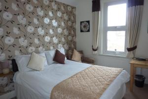 Dormitorio con cama con pared de flores en Pebbles Guest House, en Southend-on-Sea