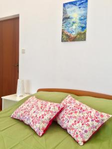 2 cuscini posti sopra un letto verde di Sobe Bosiljka a Nin