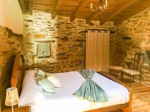 um quarto com uma cama num quarto de pedra em CASA RURAL BIERZO ENCANTADO em Valle de Finolledo