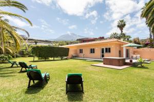 a yard with chairs and a house with mountains in the background at Finca La Gaviota - Las Palmeras in Icod de los Vinos