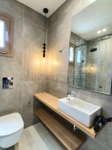 a bathroom with a sink and a toilet and a mirror at St.Thomas Beach Luxury Apartments in Pefki Rhodes