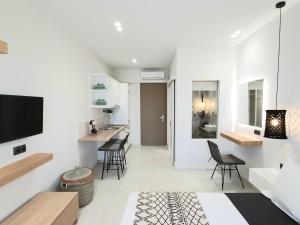 a living room with white walls and a kitchen with chairs at St.Thomas Beach Luxury Apartments in Pefki