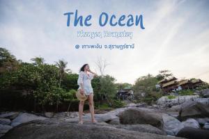 a woman standing on a rock in the ocean at The Ocean Phangan Homestay in Haad Rin