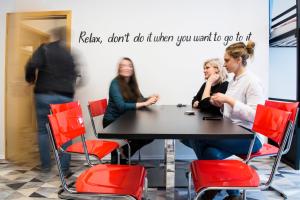 um grupo de pessoas sentadas numa mesa com cadeiras vermelhas em Hostel Eleven em Brno