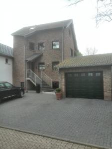 a brick house with a garage and a driveway at Ferienwohnung auf dem Kutzenberg in Altendorf