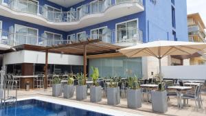 un hotel con piscina, mesas y sombrilla en Cesar Augustus, en Cambrils