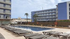 a swimming pool with lounge chairs next to a building at Cesar Augustus in Cambrils