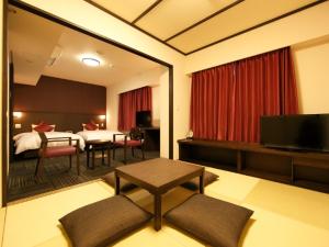 a living room with a room with a bed and a table at Dormy Inn Premium Wakayama Natural Hot Spring in Wakayama