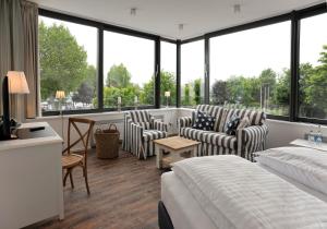 a hotel room with two beds and chairs and windows at ACQUA Strande Yachthotel & Restaurant in Strande +27 photos