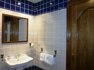 Un baño con azulejos azules, lavabo y espejo. en La Hosteria de Castroviejo, en Duruelo de la Sierra 53 fotos más