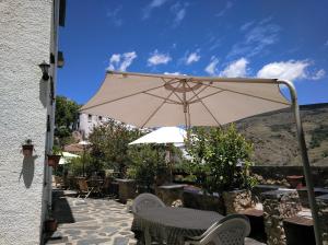 une terrasse avec un parasol, des tables et des chaises dans l'établissement El Vergel de Berchules, à Bérchules