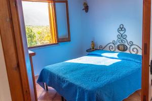 una camera blu con un letto e una finestra di Baglio Cracchiolo da Tuzzo - Casa Carrubbo a San Vito lo Capo