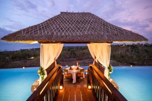 a dining table on a deck next to a pool at Semabu Hills Hotel Nusa Penida in Nusa Penida