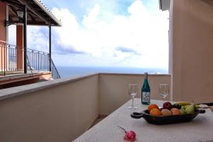a bowl of fruit and two wine glasses on a balcony at Golden Fox Studios and Suites in Lákones