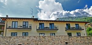 um edifício amarelo com janelas azuis e uma parede de pedra em Appartamenti Cèpo em Tremosine Sul Garda