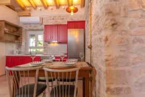 a kitchen with red cabinets and a stone wall at Ismini Kaminaki Beach in Nisakion