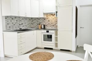 una cocina blanca con armarios blancos y fregadero en Ocean sound en Arona