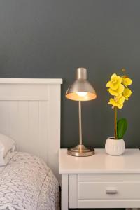 une table avec une lampe et un vase avec des fleurs jaunes dans l'établissement Founders Keepers - Leisure Isle, à Knysna