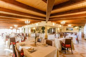 un ristorante con tavoli e sedie bianchi e soffitti in legno di Su Soi a Càbras
