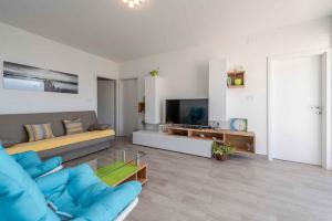 a living room with a blue couch and a television at Sea the Sunset Apartment in Zadar