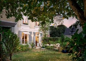 a white house with a table and chairs in the yard at La Maison Charmante in Châtellerault