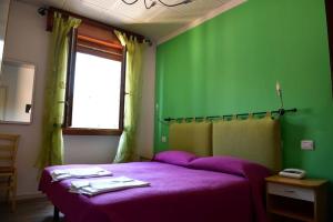 um quarto com uma cama roxa e uma parede verde em Albergo Colonna em Bertinoro