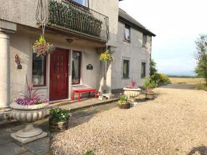 une maison avec une porte rouge et quelques plantes en pot dans l'établissement Shandon Farmhouse Bed and Breakfast, à Drymen