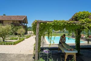 a woman sitting on a bench next to a pool at Garderes in Monlezun