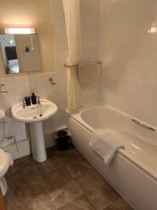 a bathroom with a sink and a tub and a toilet at Oakrooms in Swayfield